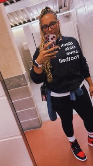 Person wearing a black sweatshirt with text, taking a mirror selfie in a bathroom.
